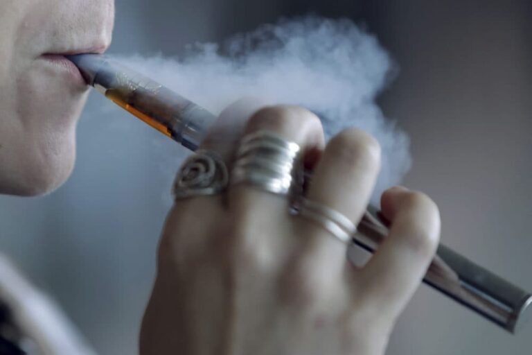 Person vaping a THC cartridge with visible vapor cloud